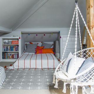 grey attic bedroom with hanging chair and patterned rug