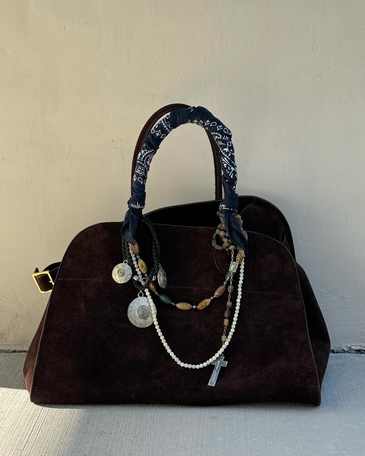 A suede bag with charms on them.