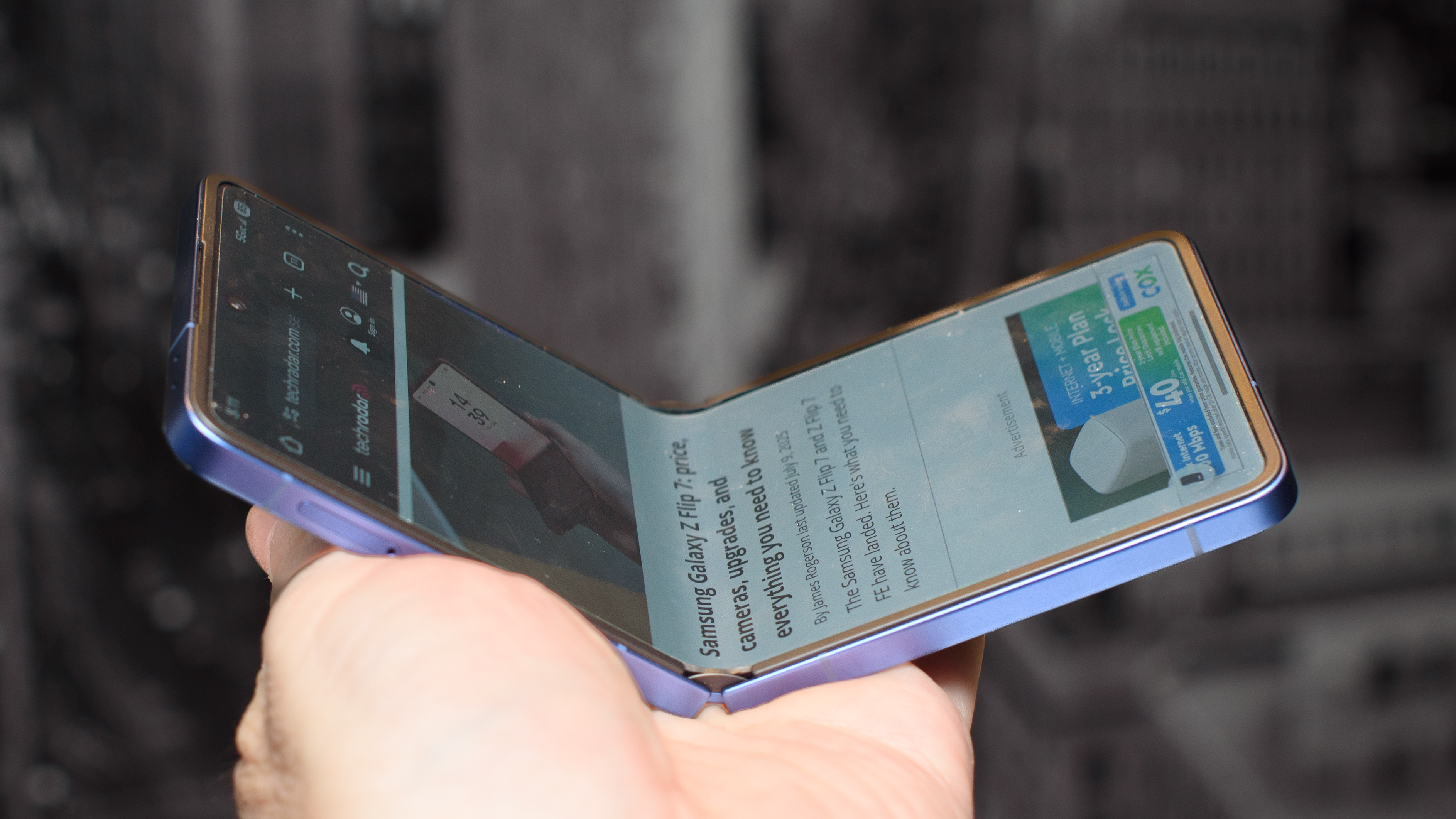 Samsung Galaxy Z Flip 7 in blue partially open showing TechRadar.com on the display