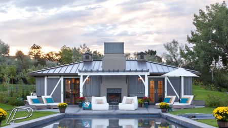 A backyard with a pool and outdoor chairs with cushions 