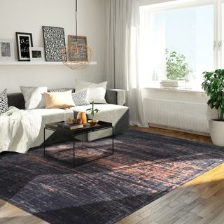 A living room with a dark patterned rug and a grey corner sofa with scatter cushions