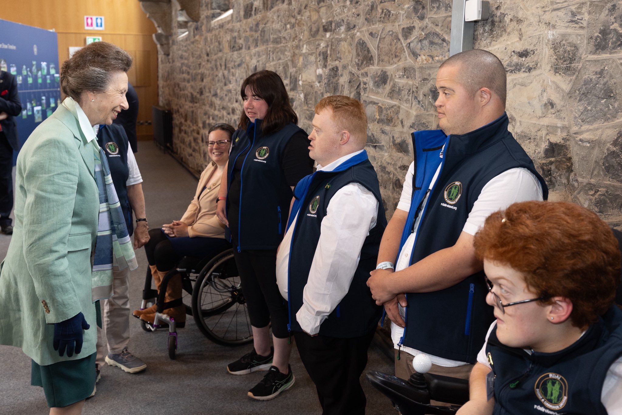 Princess Anne wearing a green blazer talking to a group of people at a horse show