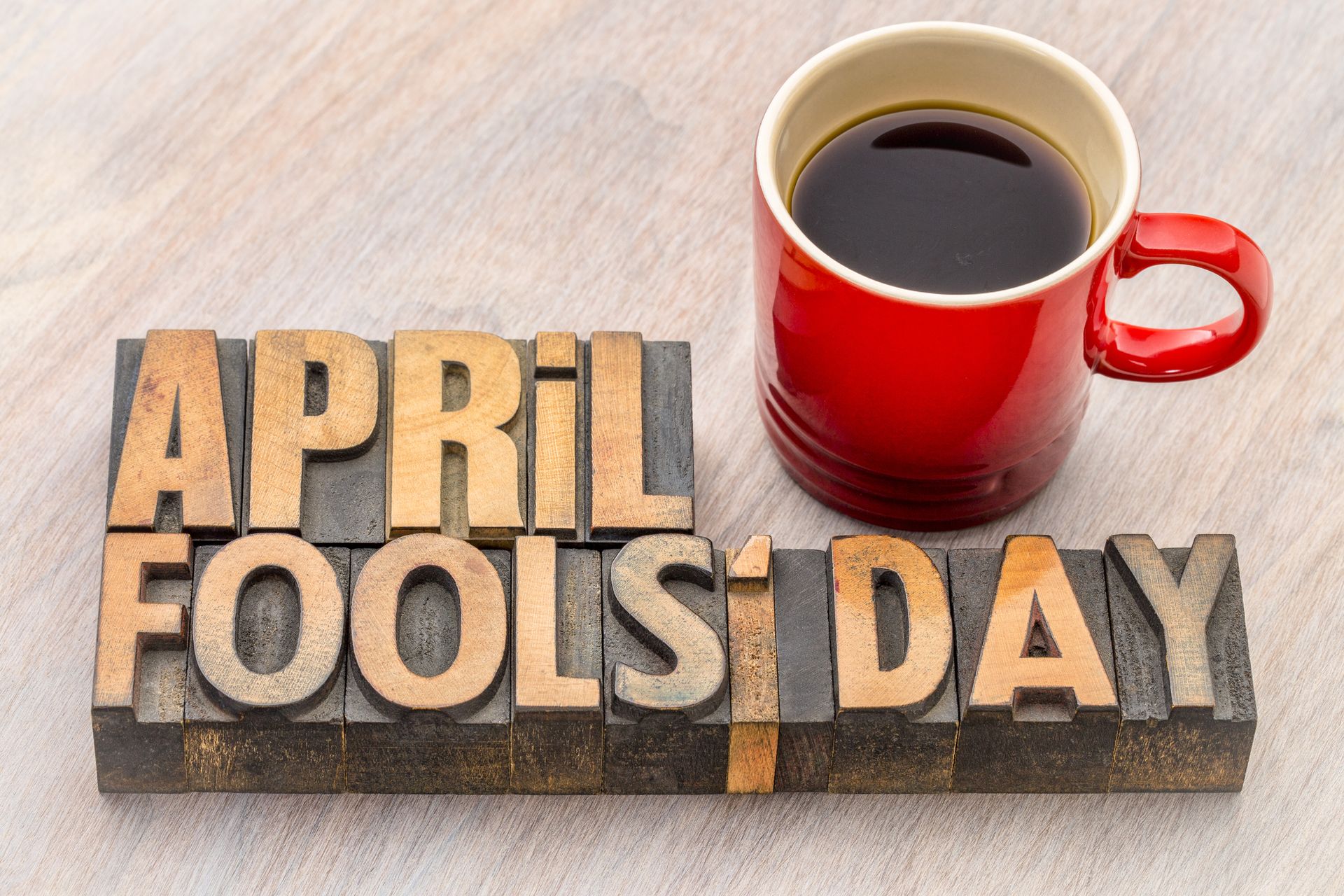 April Fools' Day word abstract in vintage lettepress wood type with a cup of coffee