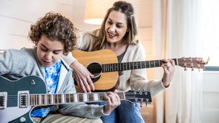 Mother and son playing guitars at home