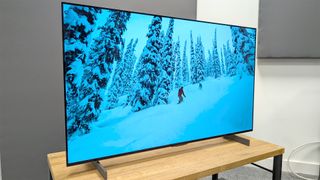 LG C4 42-inch OLED TV on wooden TV rack with snowy landscape on screen