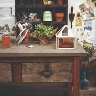 A vintage work table with plants and gardening equipment atop