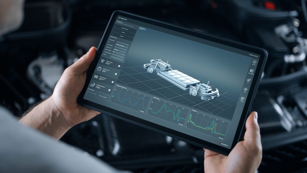 Two hands hold a tablet showing a model vehicle.