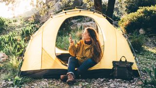 Woman sitting in tent checking phone
