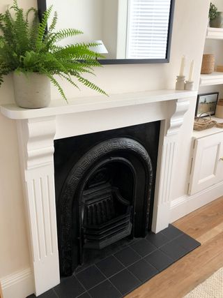The after picture showing the fireplace insert on the wall with painted fire surround and matt black heart tiles