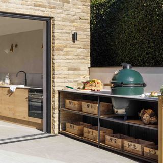 outdoor kitchen with Big Green Egg BBQ, crate storage, white worktop, view into kitchen
