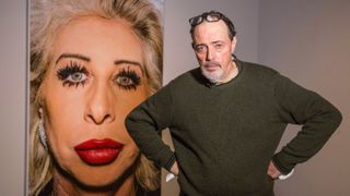 Photographer Bruce Gilden with one of his photographs, at the Barbican Art Gallery, London, 2016. The exhibition Strange and Familiar: Britain as Revealed by International Photographers, curated by Martin Parr.