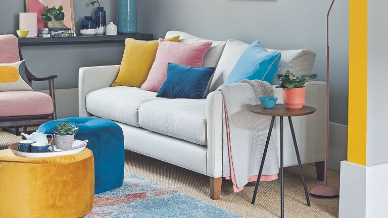 neutral living room with small off-white sofa and pops of bright colour
