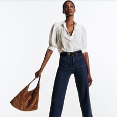 madewell model wearing white blouse, jeans, and suede bag