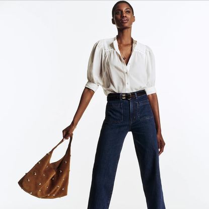 madewell model wearing white blouse, jeans, and suede bag