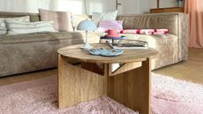 A wooden coffee table with a pink rug underneath it