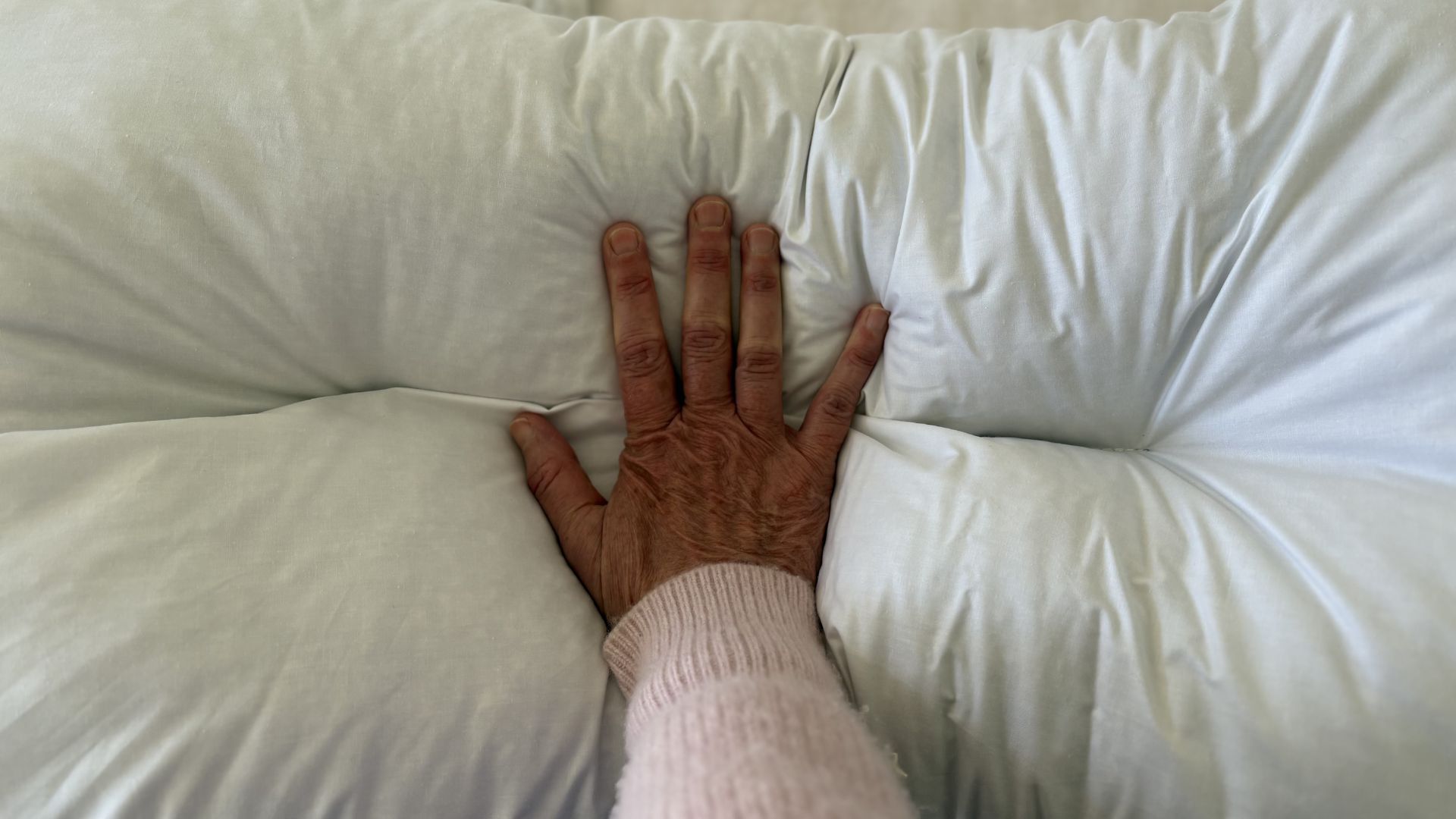 The Naturalmat The Centre Stitched Wool Pillow on a bed