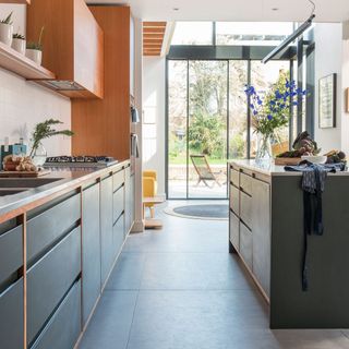 Kitchen extension with glass sliding doors and orange and grey cabinets
