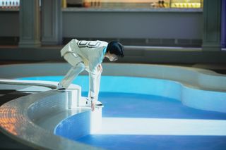 Ryu Jun-yeol as 3rd Floor, leaning over to touch a false pool, in Netflix's 'The 8 Show'