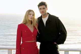 Margot Robbie in a red Chanel jacket and skirt with Jacob Elordi by the sea in Big Sur