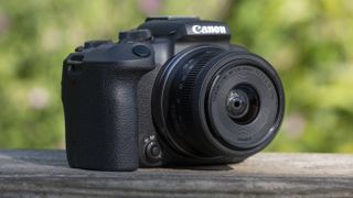 The Canon EOS R10 camera sitting on a wooden bench