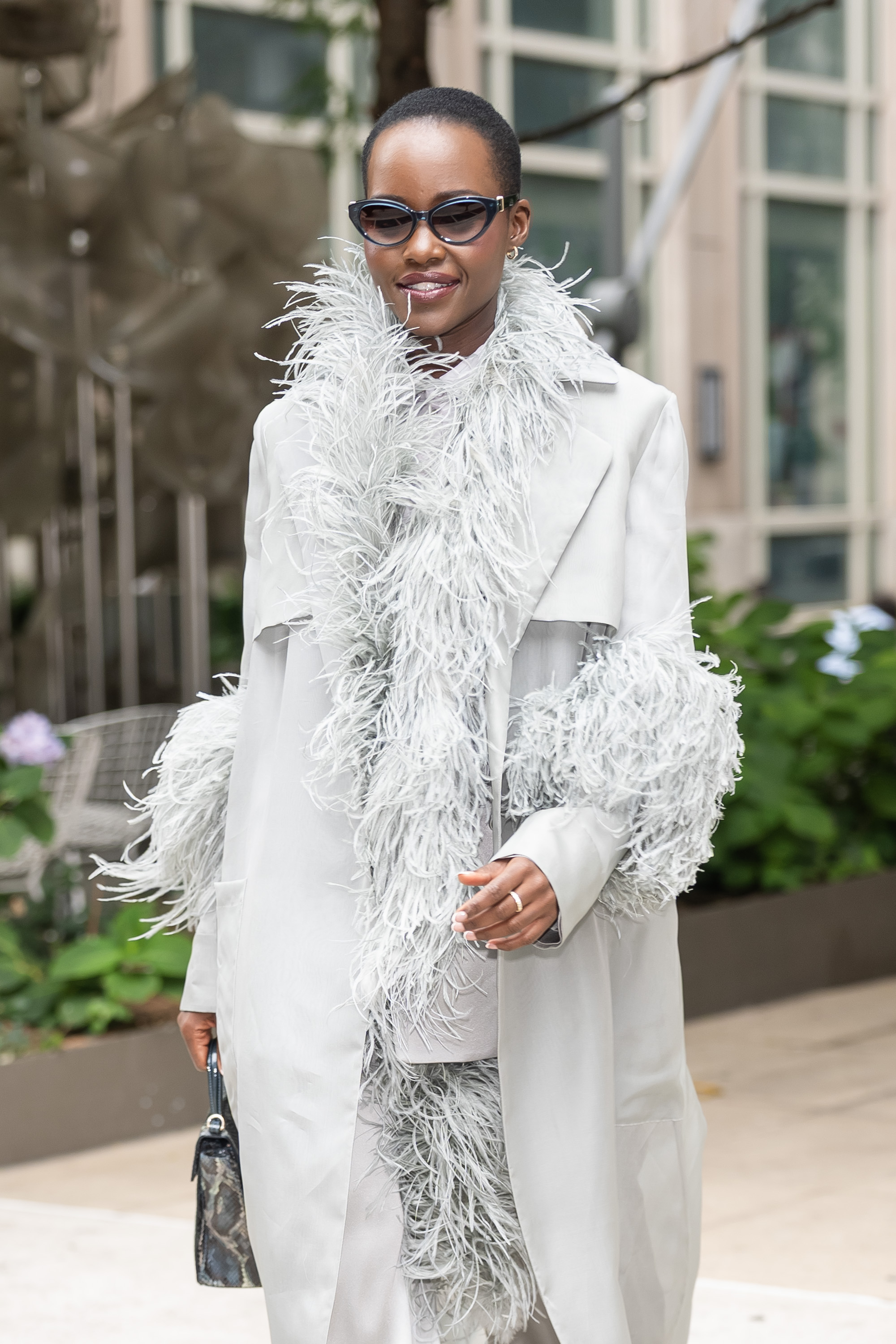 Lupita Nyong'o wearing a feathered coat on a press day.