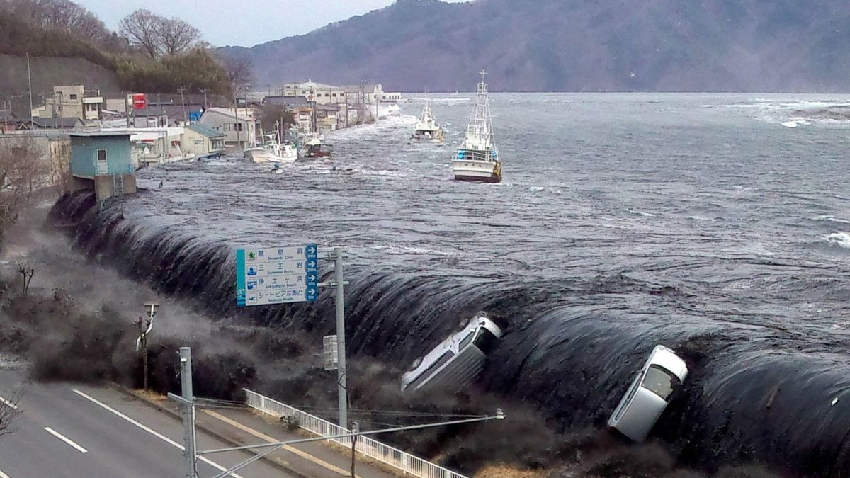 cars being swept away as a tsunami breaches an embankment