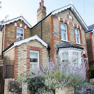 a single storey side extension to the front of a brick Victorian property, with large lavender plant in the front garden