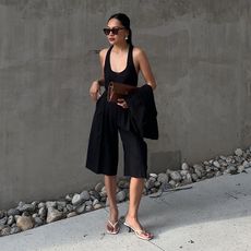 Woman wears black waistcoat, black mini skirt and basket bag