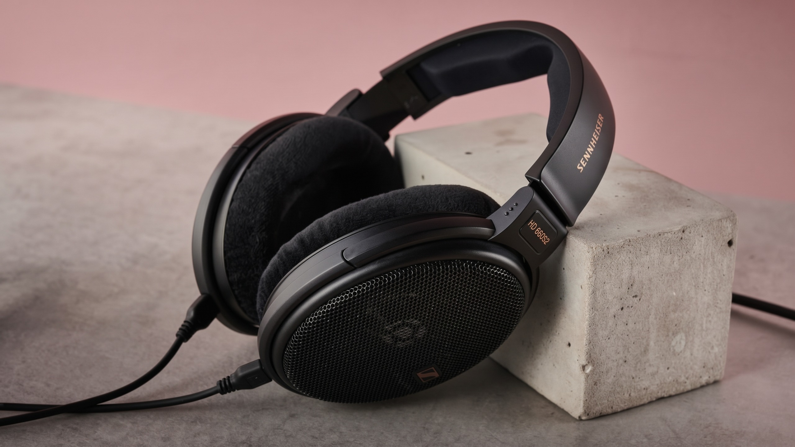 The Sennheiser HD 660S2 on top of a concrete block in front of a pink background. Edited by Gemini to remove a background product.