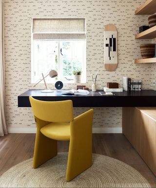 Home office with subtle wallpaper, a yellow chair and a round rug