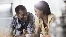 A couple laugh and smile at each other over coffee.