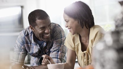 A couple laugh and smile at each other over coffee.
