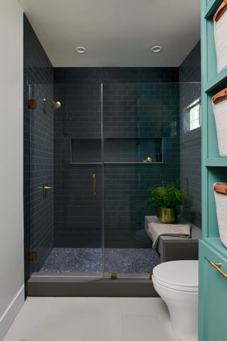 a dark blue bathroom with a niche and a shower seat