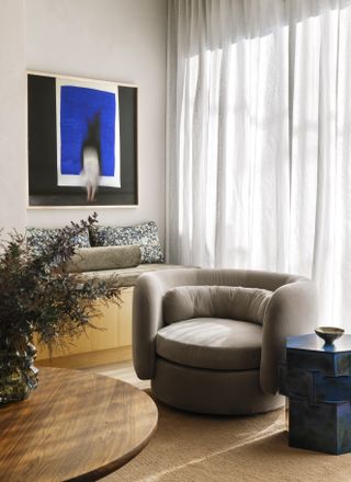 A living room with a brown/beige swivel sofa chair and a blue side table