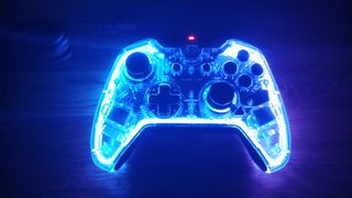 A photo of the BigBig Won game controller lit up in blue light on a table