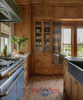 kitchen with blue range cooker and vintage rug with wooden cabinets