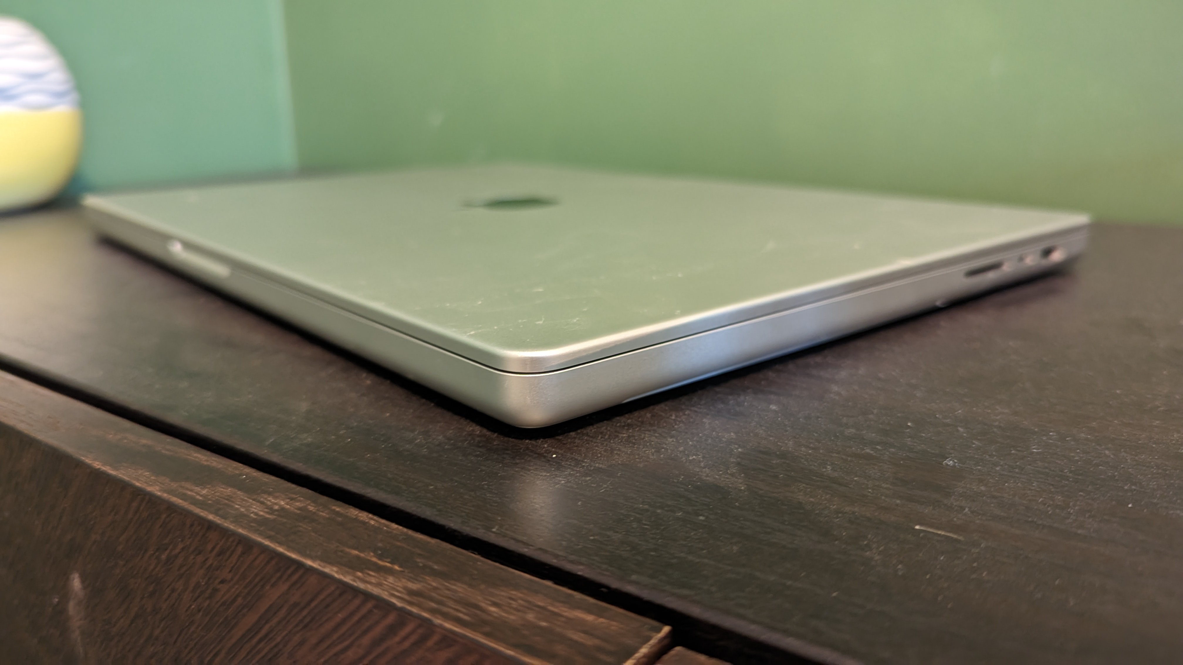 MacBook Pro 16-inch (2023) on wooden desk with green background