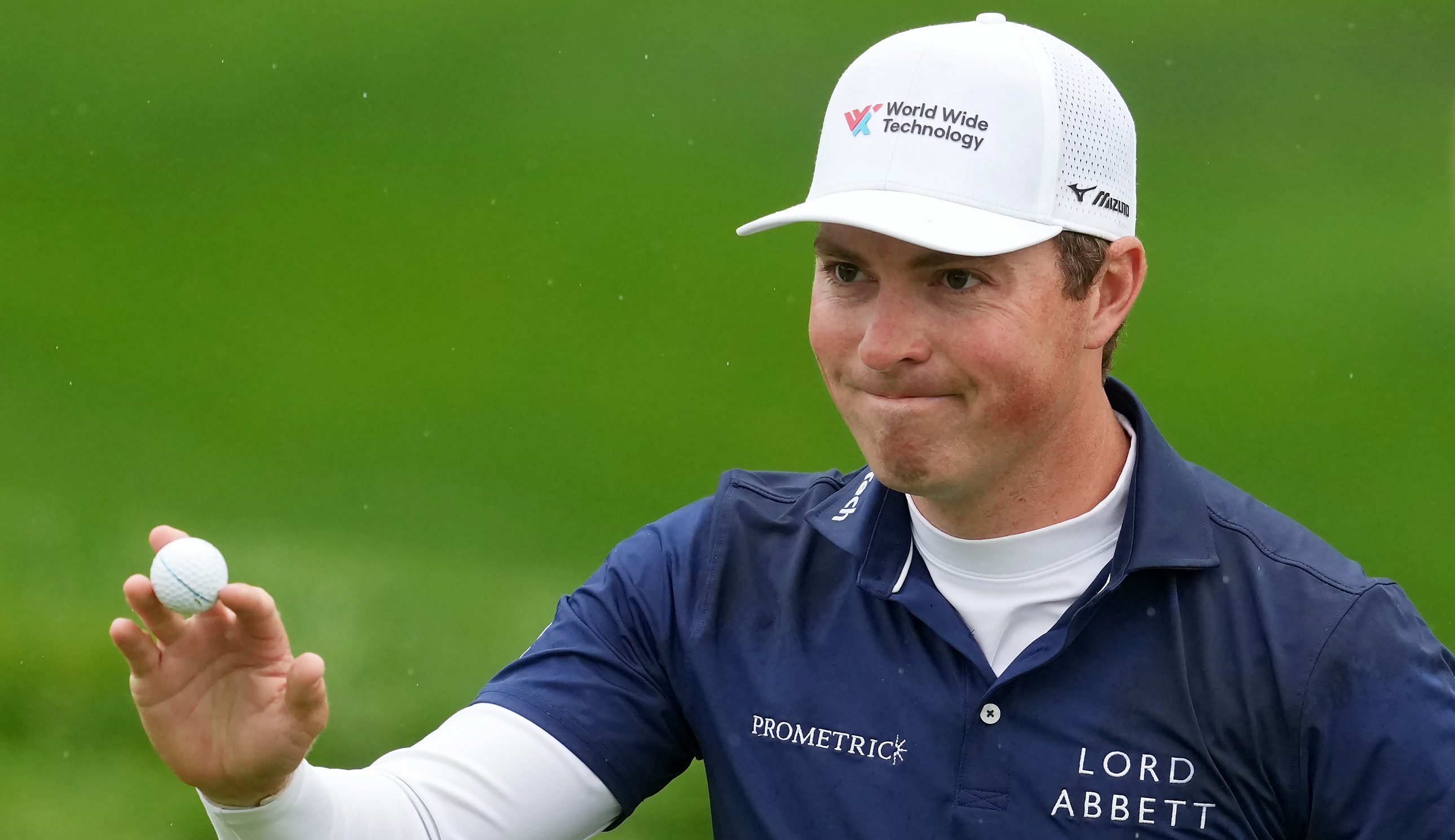 Ben Griffin waves to the crowd holding a golf ball