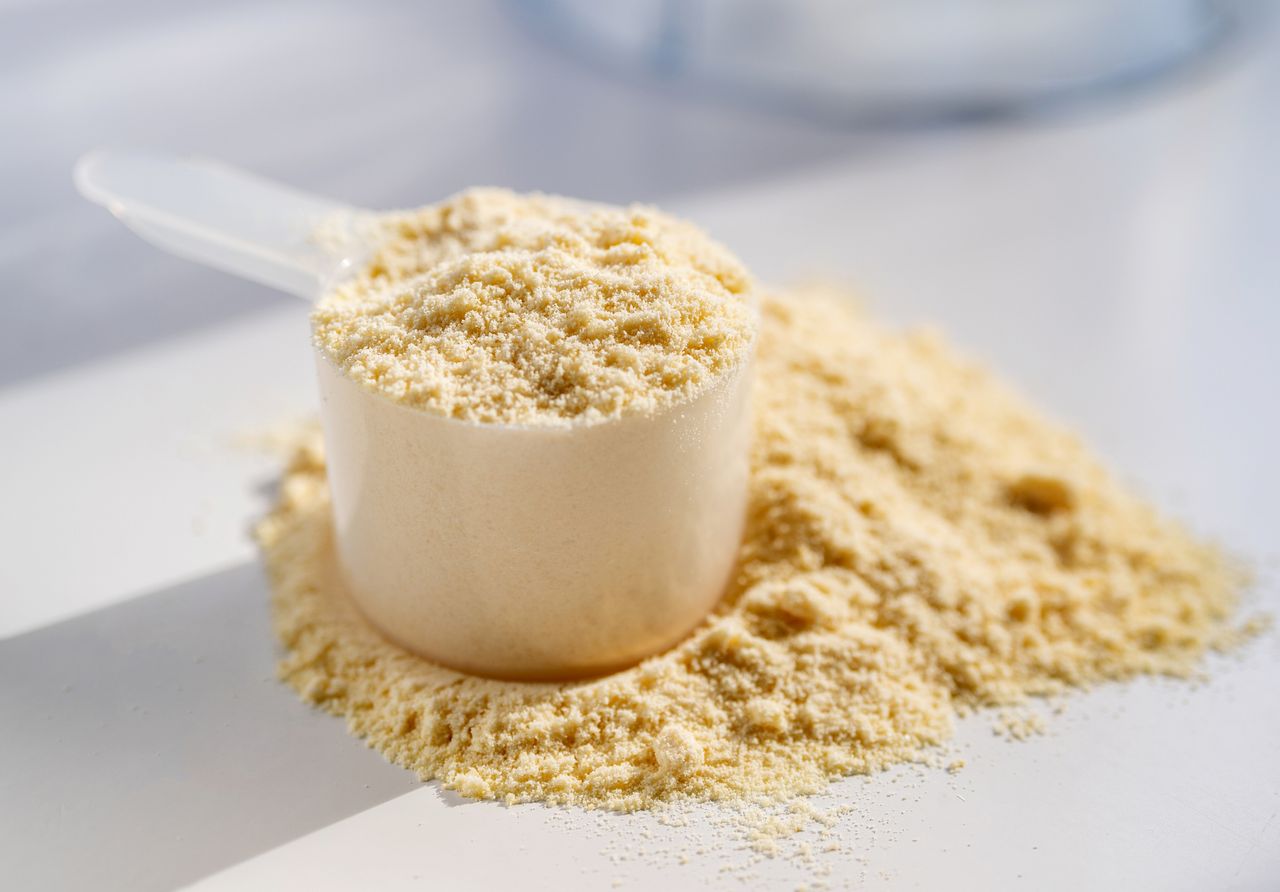 Cup of protein powder on white table