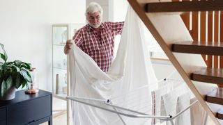 Man draping sheets on the clothes rack to dry inside