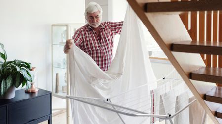 Man draping sheets on the clothes rack to dry inside