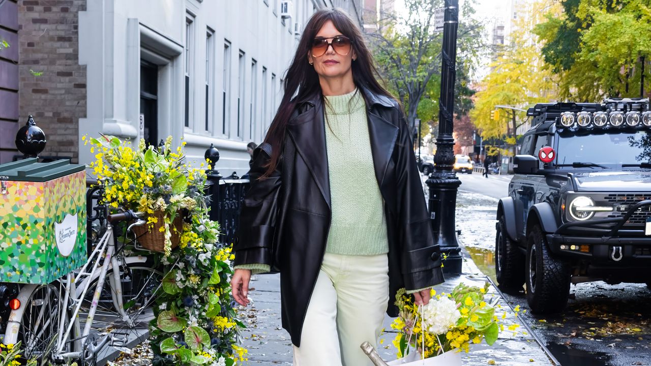 Katie Holmes in a green sweater, green pants, and black jacket