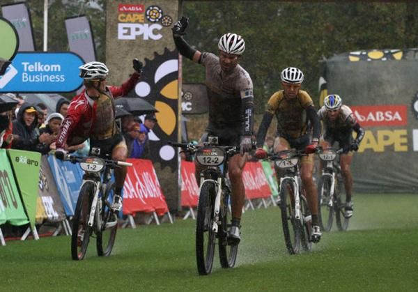 Tim Boehme of the Bulls hits his handlebars in frustration as Burry Stander and Christoph Sauser of 36One-Songo-Specialized celebrate stage 5 win during stage 5 of the 2012 Absa Cape Epic Mountain Bike stage race from the Overberg Primary