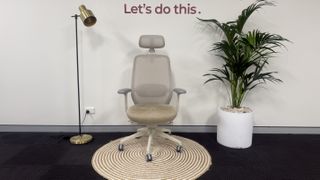The Desky CoilFlex office chair on a rug next to a lamp and a plant