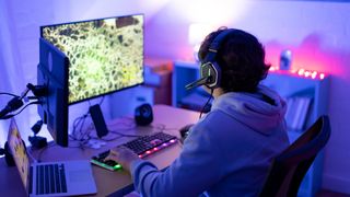 Teenager playing on a gaming PC with two monitors