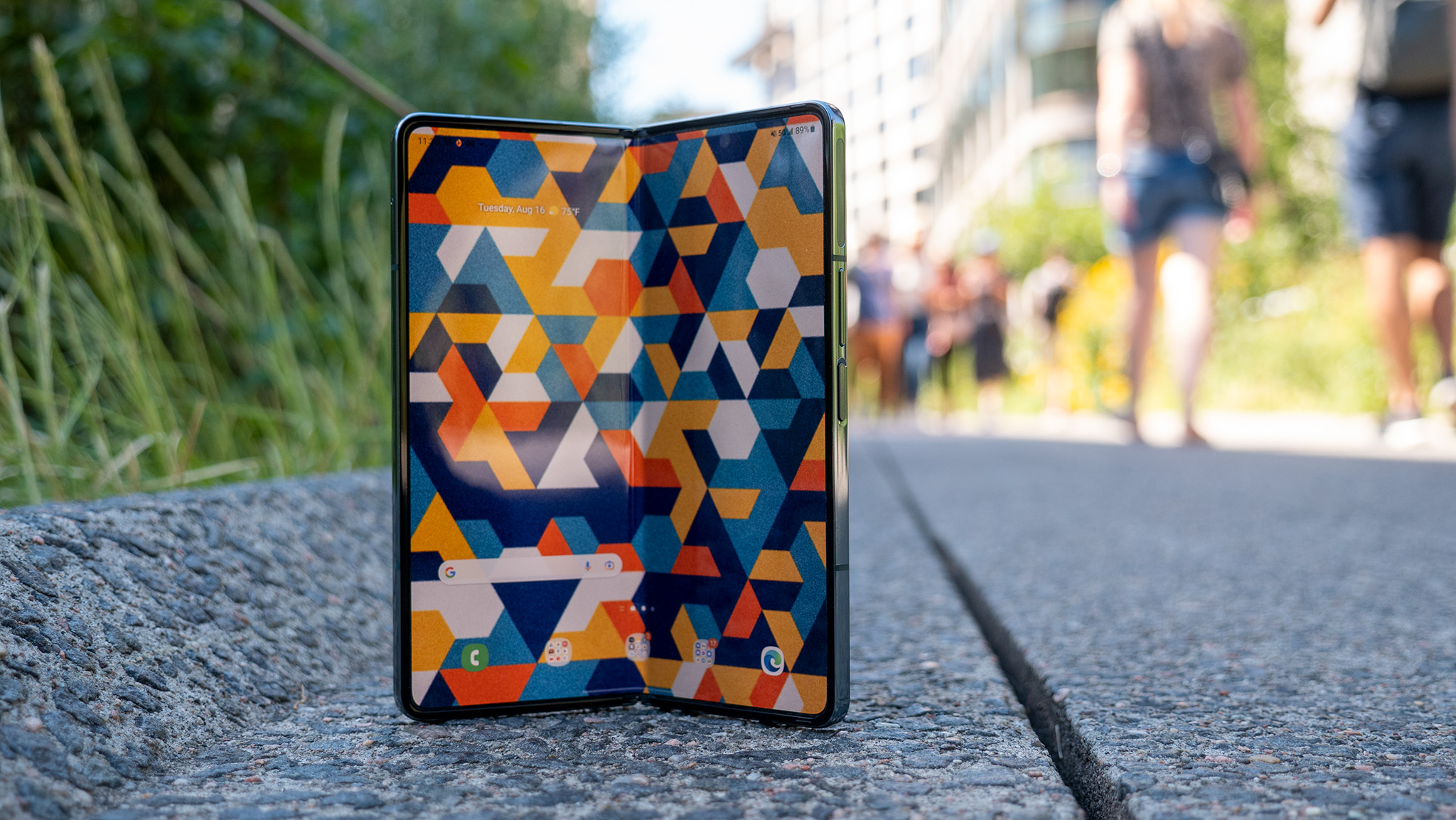 The Samsung Galaxy Z Fold 4 tented on a sidewalk with pedestrians in the background