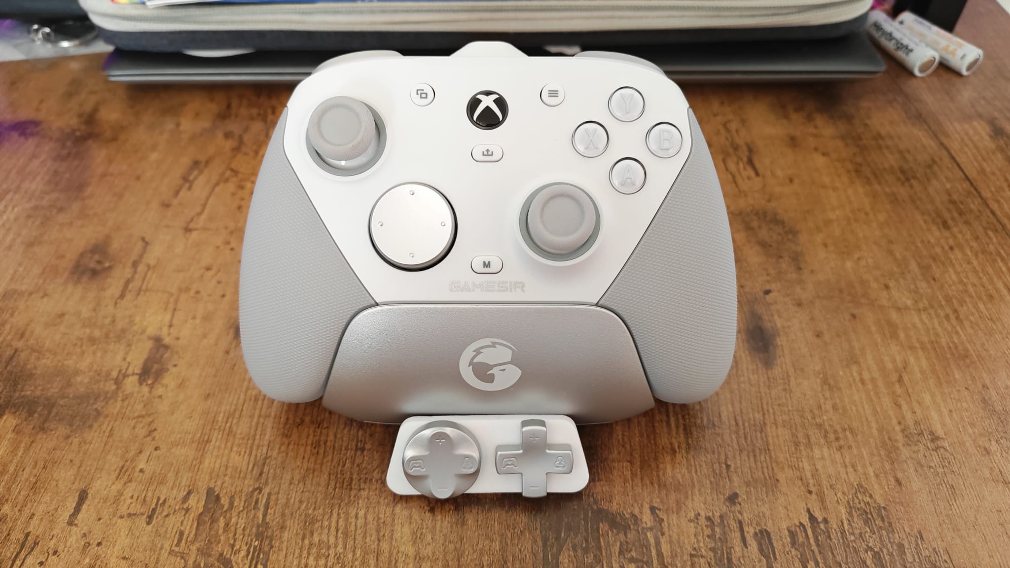 The GameSir G7 Pro on its charging stand, next to its D-pad replacements