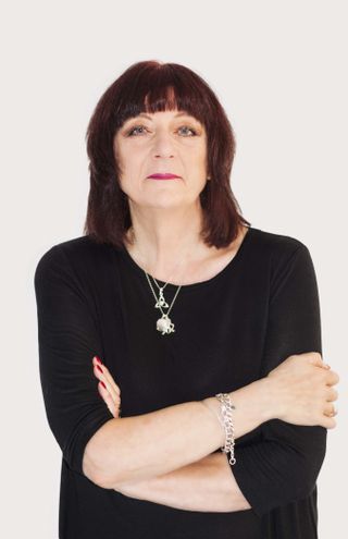 Portrait of Cosey Fanni Tutti wearing a black top on a white background