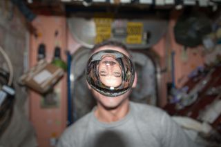 Canadian Space Agency astronaut Chris Hadfield, Expedition 34 flight engineer, watches a water bubble float freely between him and the camera, showing his image refracted, in the Unity node of the International Space Station. Image released Jan. 21, 2013.