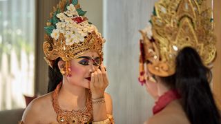 Legong dancer applying makeup